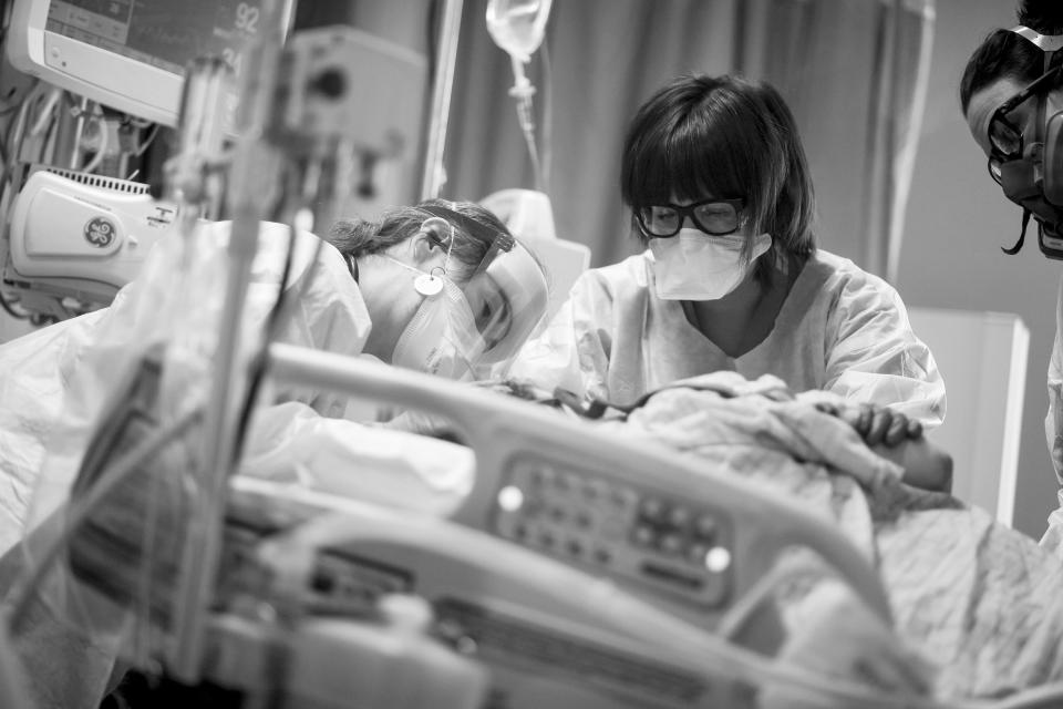 Image: Dr. Carrie Goodson left, comforts a patient as she is intubated, while nurses Ashley Vite, center, and Amy Cooper assist in the ICU Covid ward at the Medical Center of Aurora, in Colorado on May 27, 2020. (AAron Ontiveroz / The Denver Post via Getty Images file)