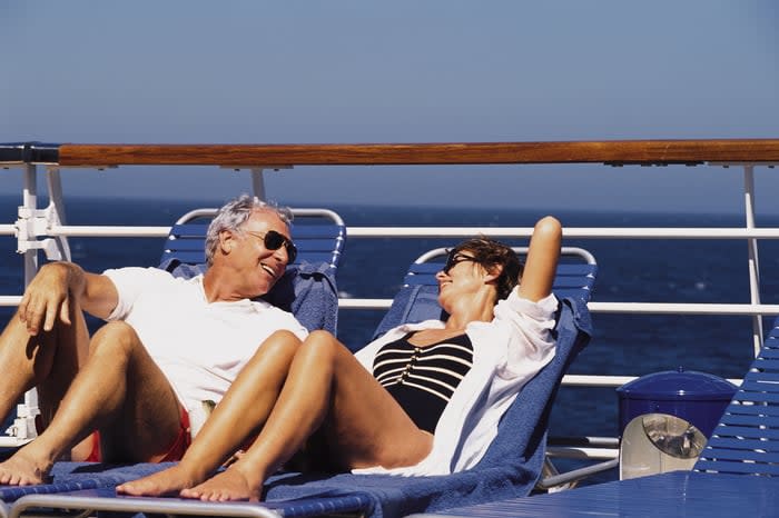 Two people lying on chairs aboard a ship.