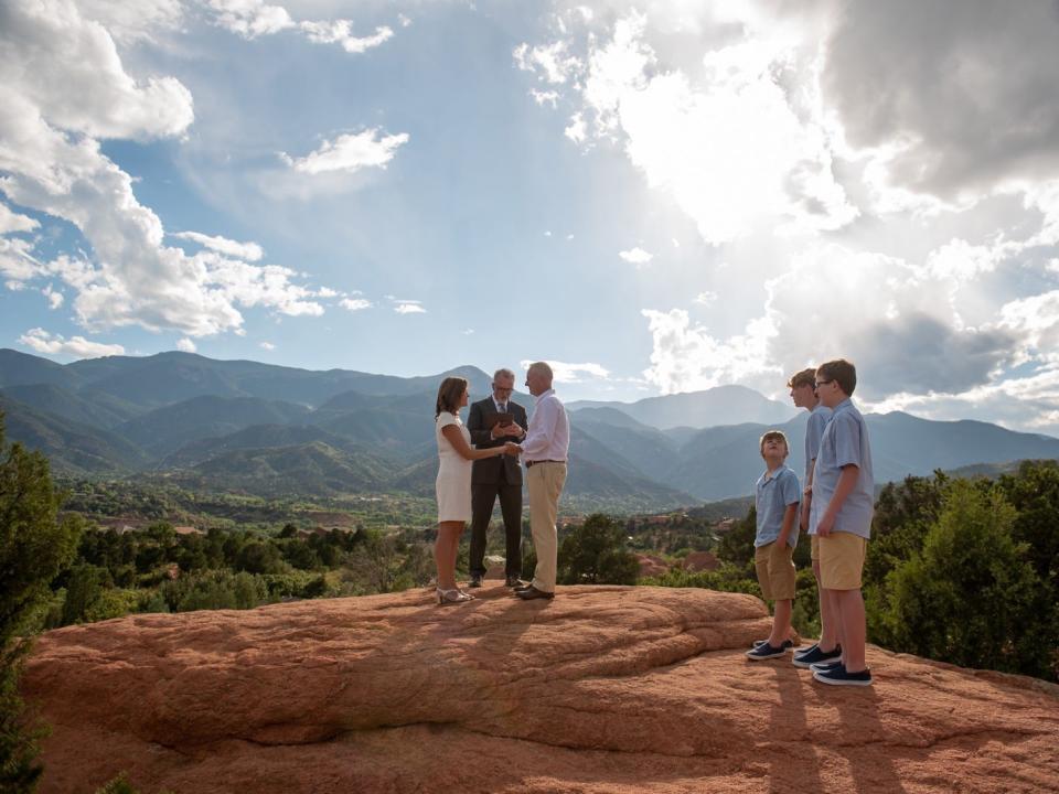 Man and woman getting married with scenic Colorado backdrop, three kids are watching nearby