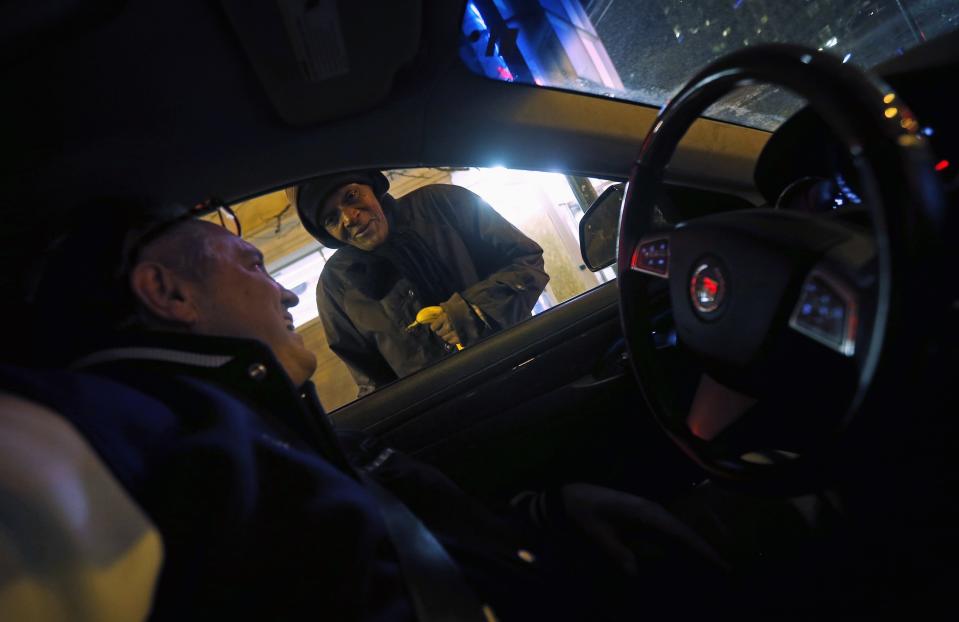 Patrick Angelo, en el interior de su coche, entrega comida a una persona sin hogar. REUTERS/Jim Young