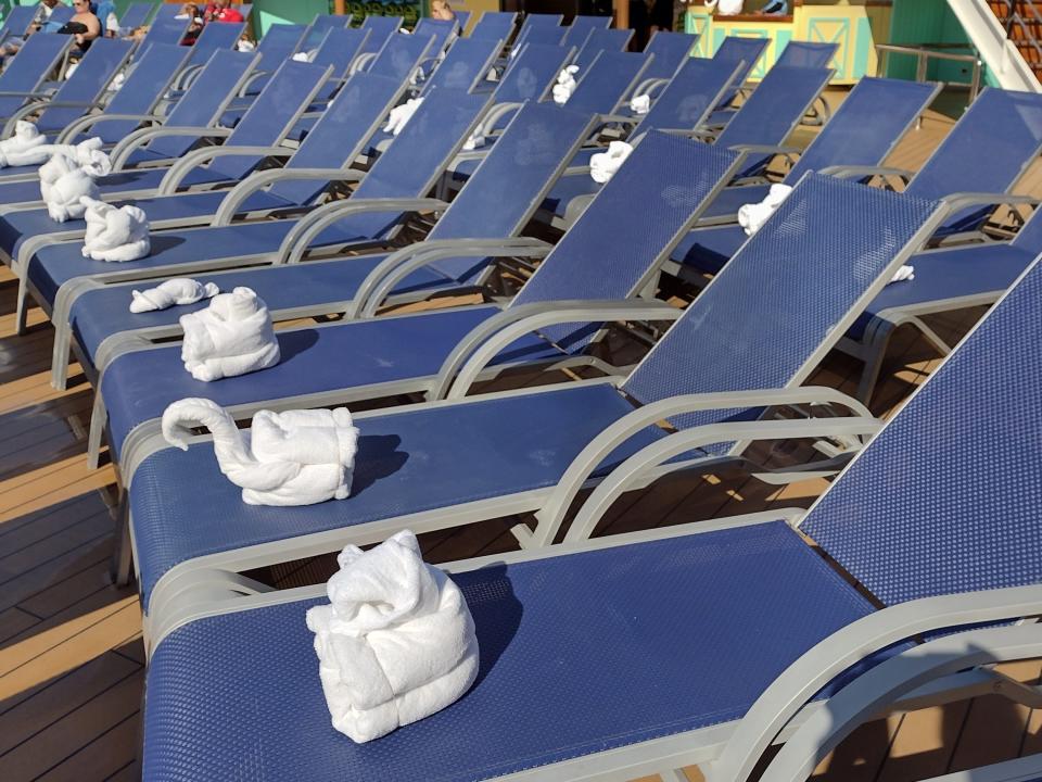 Rows of pool lounge chairs with towels folded like animals on each.