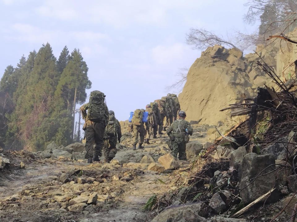 自衛隊成員攜同物資徒步進入石川縣其中一個重災區珠洲市。（美聯社）