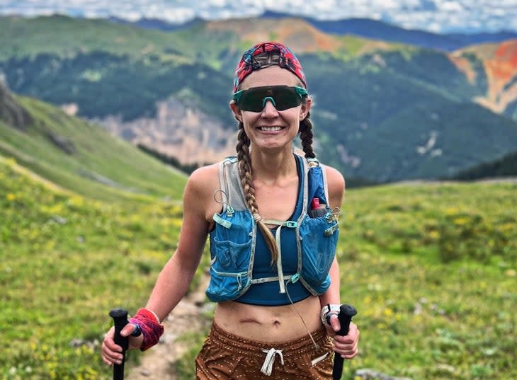 A woman in a backwards cap with trekking poles