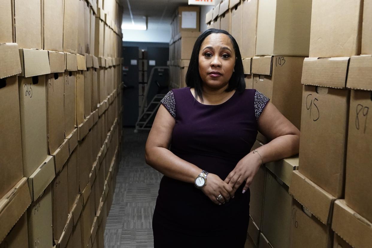 Fulton County District Attorney Fani Willis stands among tall stacks of cardboard boxes.