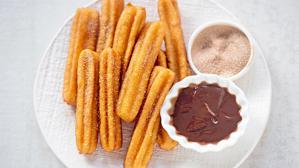 Homemade air fryer churros served on a plate with cinnamon sugar and chocolate sauce