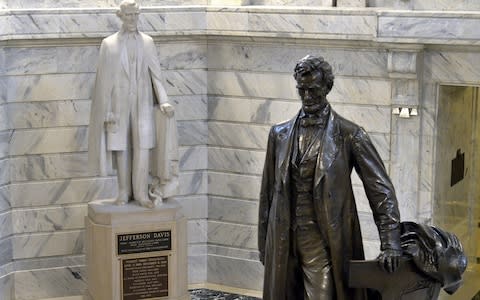 In this Aug. 5, 2015 file photo, a statue of Jefferson Davis, left, faces a statue of Abraham Lincoln in the Rotunda of the state Capitol in Frankfort, Ky. A panel of historic properties advisers in Kentucky on Thursday, Sept. 21, 2017, has recommended removing a plaque from the statue of Jefferson Davis that identifies the only president of the Confederacy as a "patriot, hero, statesman." - Credit: AP