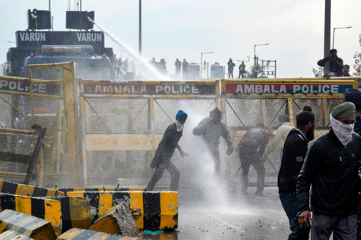 Police block a road and use a water cannon to disperse farmers marching to India’s capital on Thursday (AFP via Getty Images)