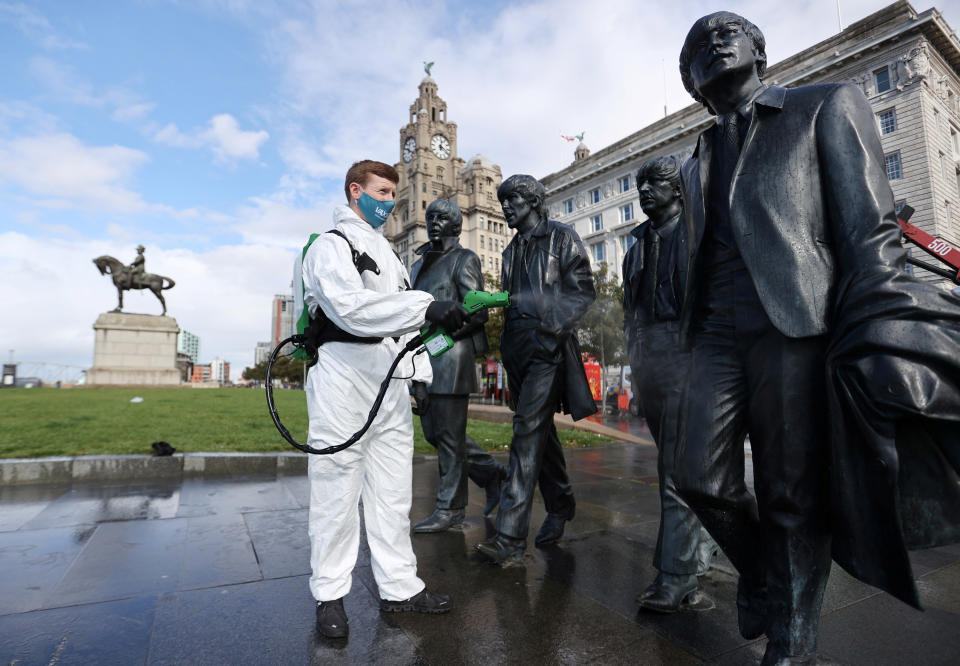 A man disinfects a statue of the Beatles amid the outbreak of the coronavirus disease (COVID-19), in Liverpool, Britain October 1, 2020. REUTERS/Carl Recine REFILE - CORRECTING CITY IN HEADLINE