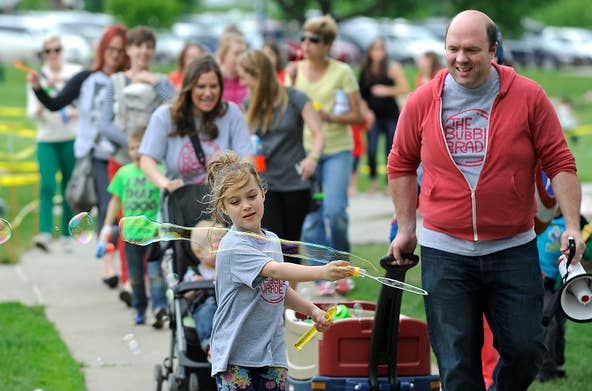Emerson Weber, 6, leads The Bubble Parade with her dad, Hugh, at Falls Park in Sioux Falls, S.D., Friday, May 15, 2015.