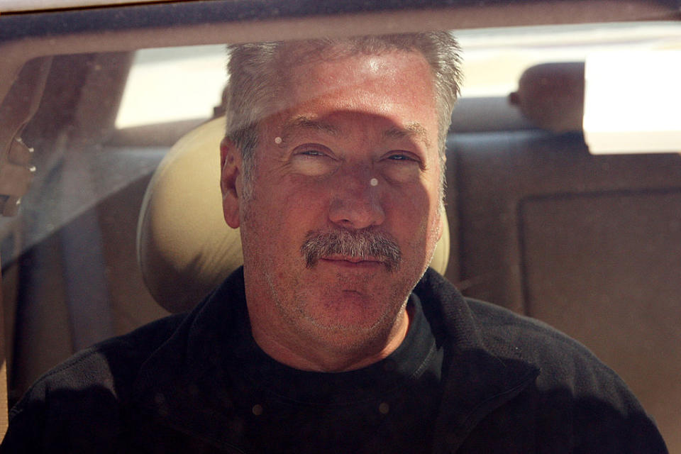 Drew smiling and sitting in a vehicle behind a window