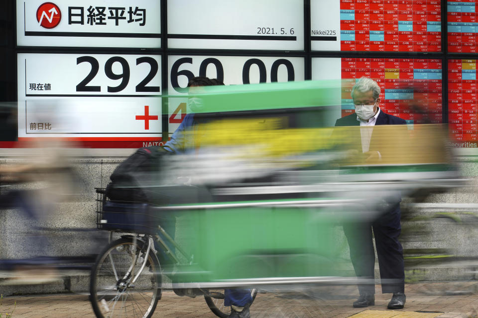 A man wearing protective mask waits for traffic light in front of an electronic stock board showing Japan's Nikkei 225 index at a securities firm Thursday, May 6, 2021, in Tokyo. Asian shares were mixed Thursday on cautious optimism about upcoming company earnings reports showing some recovery from the damage of the coronavirus pandemic. (AP Photo/Eugene Hoshiko)