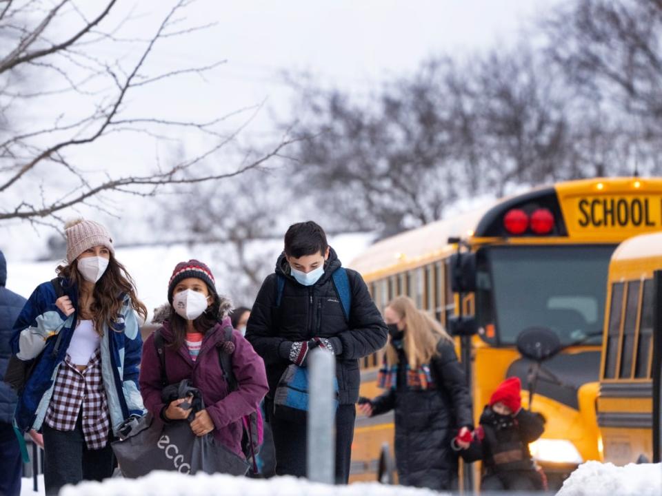 Students exit school buses as they return for in-class learning at an elementary school in Mississauga, Ont., on Jan. 19. (Nathan Denette/The Canadian Press - image credit)