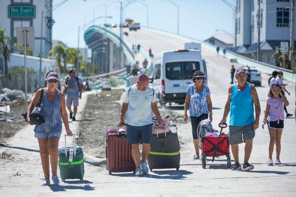 Fort Myers Beach residents walk northbound on San Carlos Boulevard after retrieving belongings from home and descending the bridge over Matanzas Harbor after Hurricane Ian passed through the region Wednesday afternoon in Fort Myers, FL., on Friday, September 30, 2022.