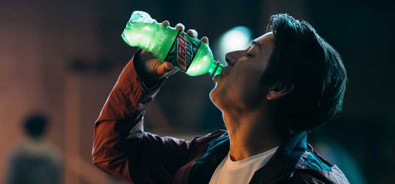 A man drinks a bottle of Mt. Dew.