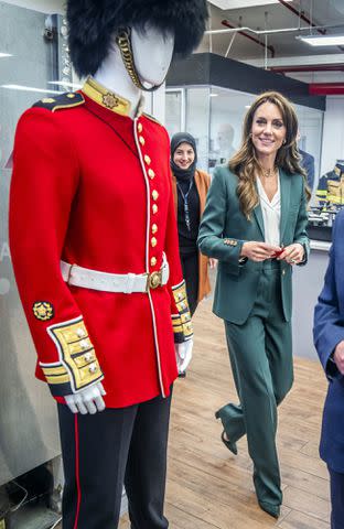 <p>Danny Lawson - WPA Pool/Getty</p> Kate Middleton views Guardsman's scarlet tunic during a visit to AW Hainsworth on Sept. 26