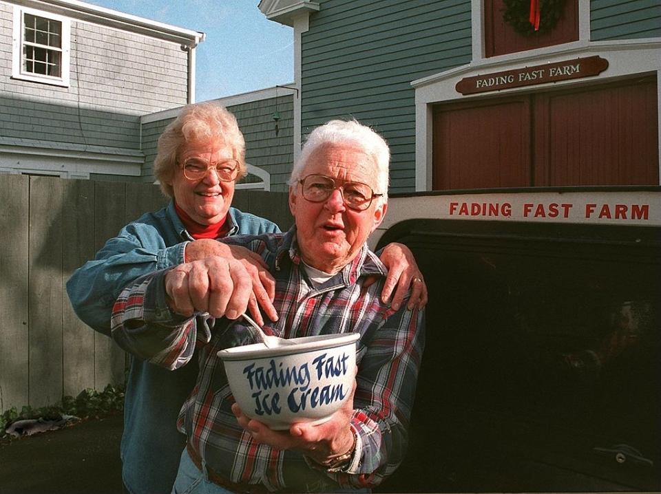 An older couple standing in front of a "Fading Fast Farm" sign, holding a large bowl labeled "Fading Fast Ice Cream". They appear to be serving ice cream