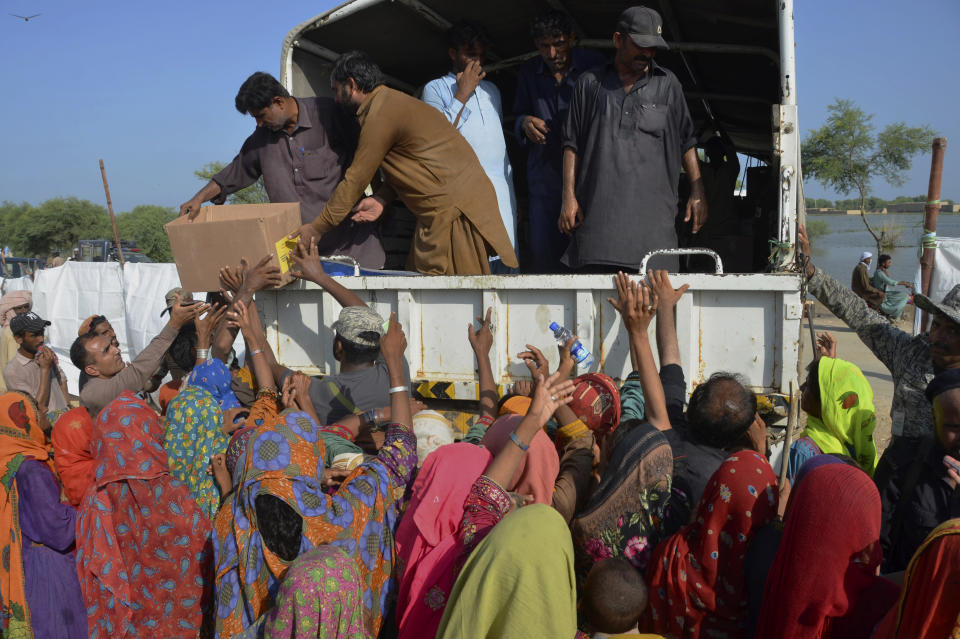 Displaced families, who fled their flood-hit homes, jostle to get relief aid distributed by soldiers of Pakistan rangers, in Dera Allahyar, in Jaffarabad, a district of southwestern Balochistan province, Saturday, Sept. 17, 2022. The devastating floods affected over 33 million people and displaced over half a million people who are still living in tents and make-shift homes. The water has destroyed 70% of wheat, cotton and other crops in Pakistan. (AP Photo/Zahid Hussain)