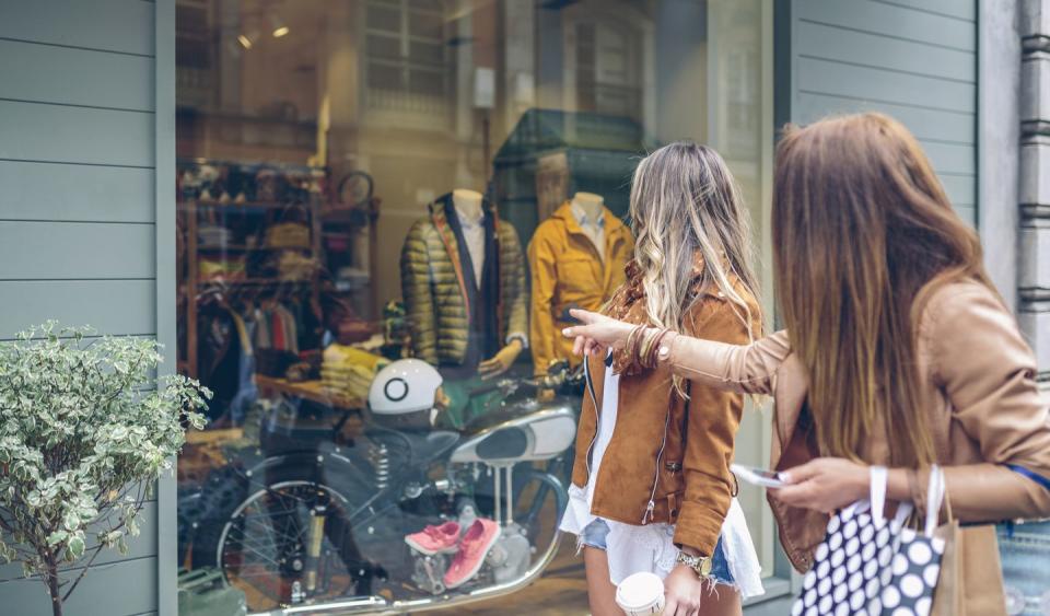 two women looking at shop window of a boutique