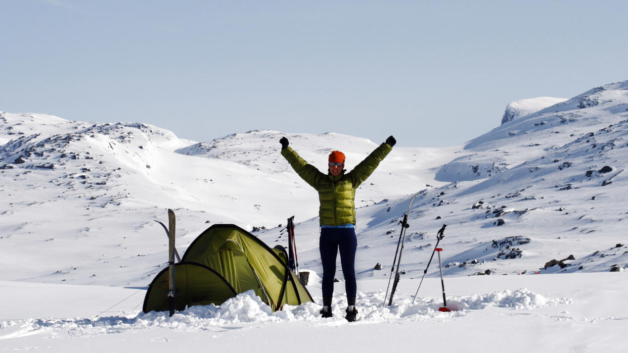  Winter camping: a hiker celebrates after setting up camp. 