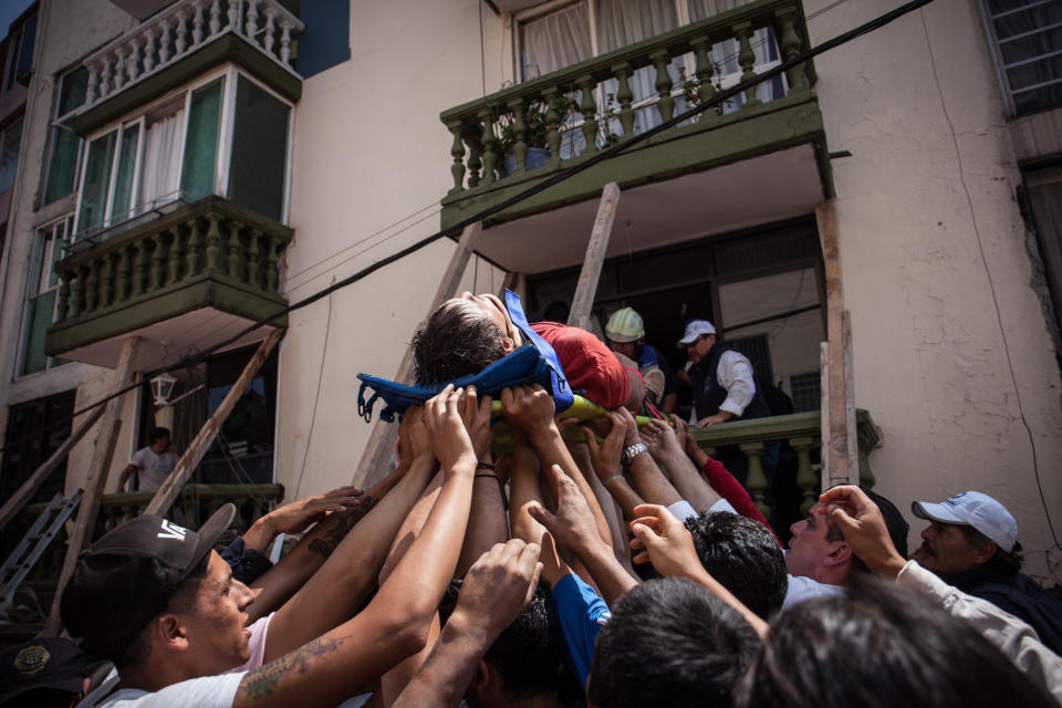 Rescuers and residents assist an injured victim amid the ruins of a building that was knocked down.&nbsp;