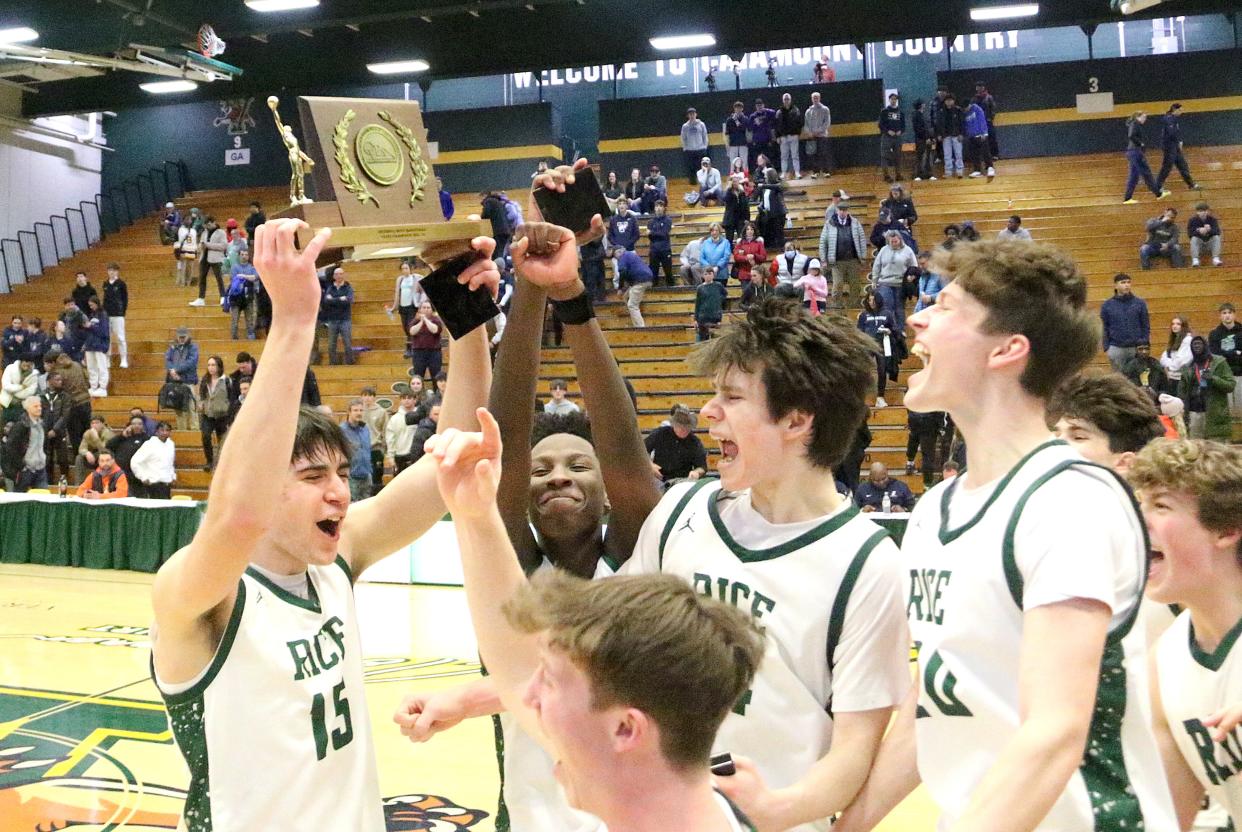 Rice captain Drew Bessette (15) brings the trophy to his teammates after their 66-63 win over Burlington in the 2024 D1 State Championship game at UVM's Patrick Gym.