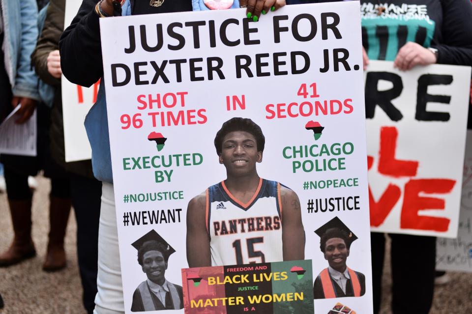 Person holding a sign with text "Justice for Dexter Reed Jr." with details of his shooting and support for Black Lives Matter