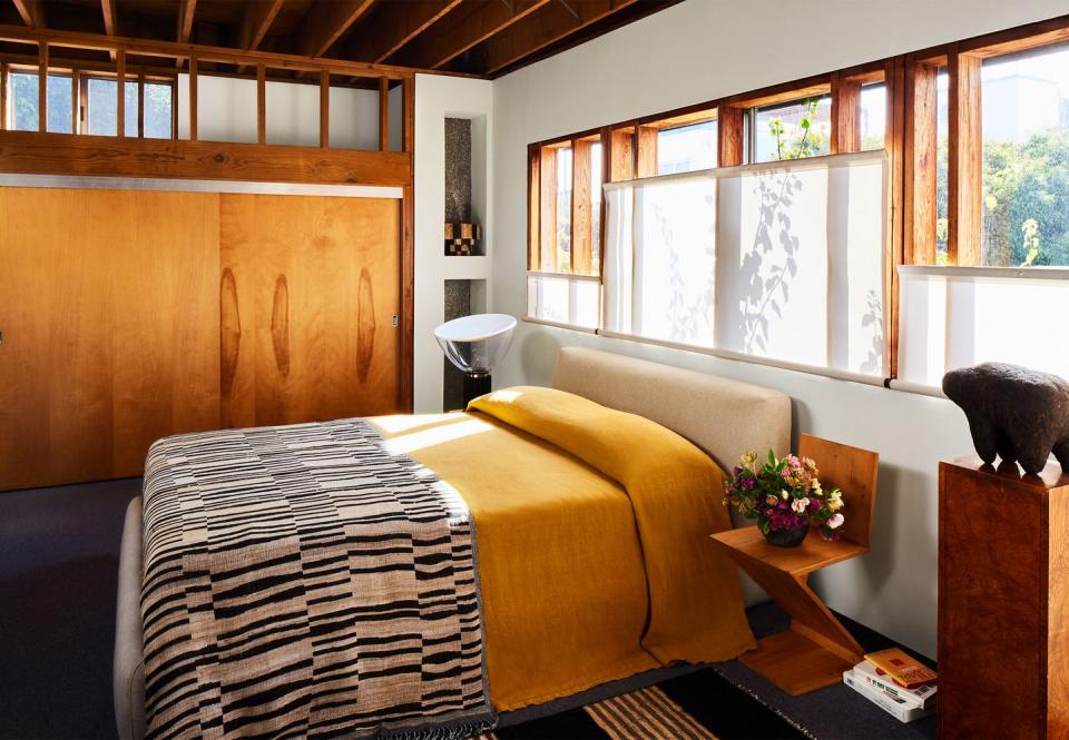 primary bedroom with many wood elements like wall paneling, windowpanes, and angular bedside chair