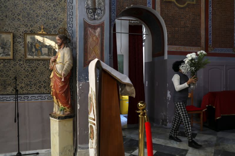 Faithful Lucia Marcano, carries a bouquet of flowers inside the Catholic Church of the Assumption of Virgin Mary on the island of Lesbos