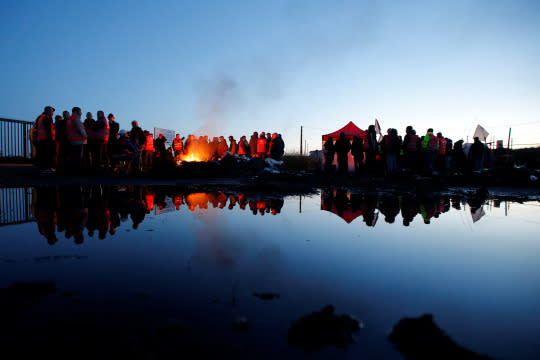 <p>French workers and protesters stand near a burning barricade to block the entrance of a depot near an oil refinery in Donges, France, May 23, 2016. (Stephane Mahe/Reuters) </p>