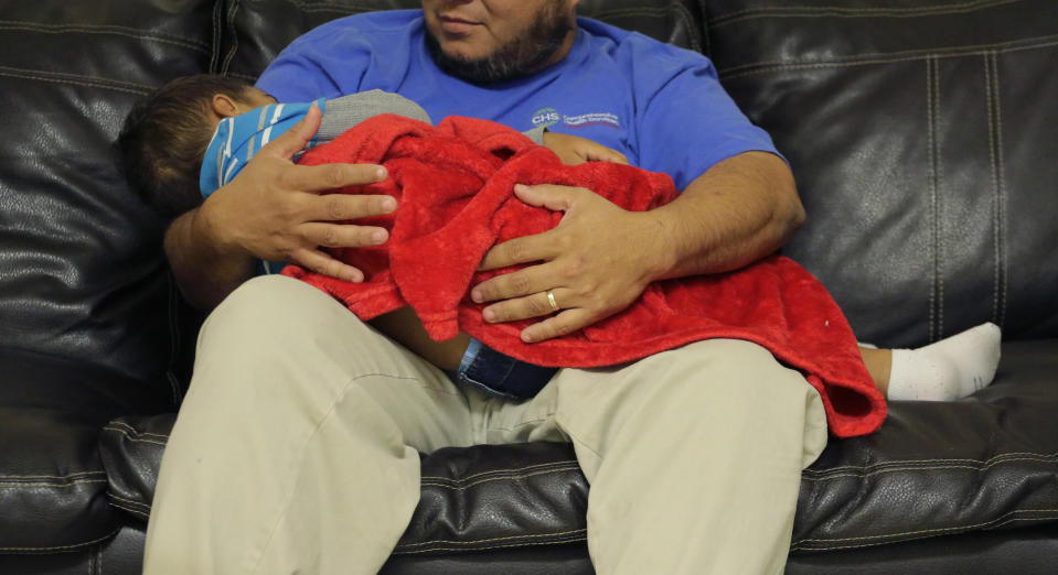 A migrant toddler is cradled by a Comprehensive Health Services, Inc. caregiver at a "tender-age" facility for babies, children and teens, in Texas' Rio Grande Valley, Thursday, Aug. 29, 2019, in San Benito, Texas. Sheltering migrant children has become a booming business for Comprehensive Health Services, a Florida-based government contractor, as the number of children in government custody has swollen to record levels over the past two years. (AP Photo/Eric Gay)