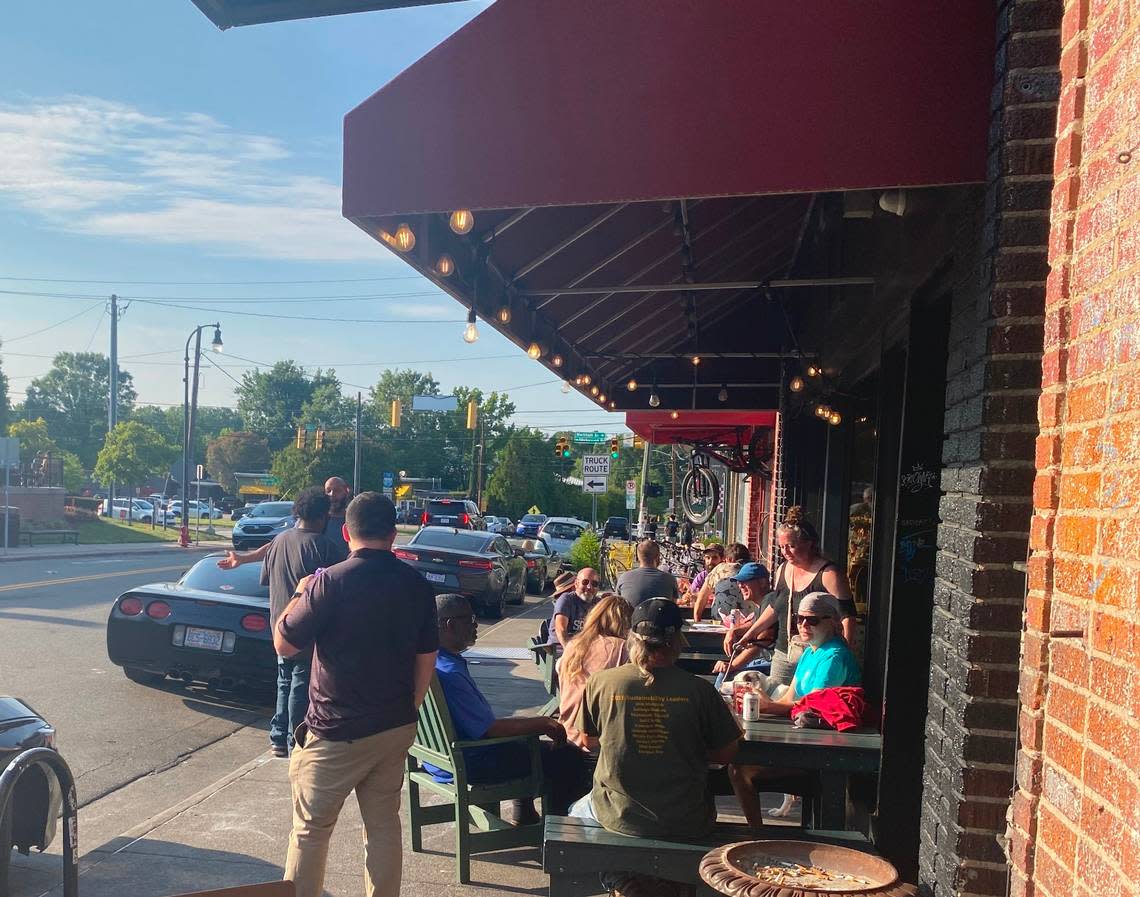 People sitting in the sun outside Dain’s Place on 9th Street in Durham.