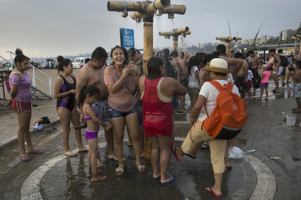 In this Feb. 15, 2020 photo, beachgoers rinse off their bodies of sand and salt after swimming in the Pacific Ocean waters at Agua Dulce beach in Lima, Peru. (AP Photo/Rodrigo Abd)