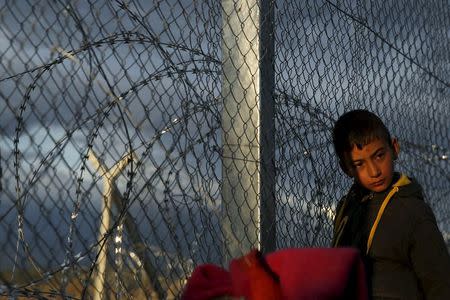 A migrant who is waiting to cross the Greek-Macedonian stand by the border fence at a makeshift camp, near the village of Idomeni, Greece, March 4, 2016. REUTERS/Marko Djurica