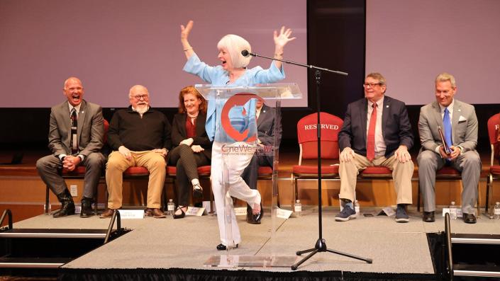 Terry B. Rogers, a former elementary school teacher, leads the audience in some mid-press conference stretches during the announcement of the renaming of the Terry B. Rogers College of Education and Social Sciences at West Texas A&amp;M University. Seated behind her are Dr. Todd Rasberry, vice president for philanthropy and external relations; Jim J. Brewer and Leah McLain, One West campaign leaders; WT President Walter V. Wendler (behind Rogers); Dyke Rogers; and Dr. Neil Terry, WT provost and executive vice president for academic affairs.