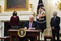 President Joe Biden signs executive orders after speaking about the coronavirus, accompanied by Vice President Kamala Harris, left, and Dr. Anthony Fauci, director of the National Institute of Allergy and Infectious Diseases, right, in the State Dinning Room of the White House, Thursday, Jan. 21, 2021, in Washington. (AP Photo/Alex Brandon)