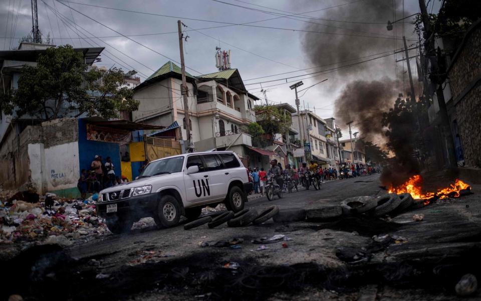  A United Nations vehicle drives past a barricade of burning tires during a demonstration against high prices and fuel shortages in Port-au-Prince - AFP