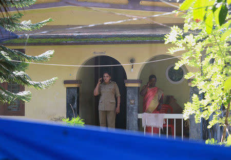 Police officers speak on their mobile phones as they stand on the porch of the house of K M Ashokan, father of 24-year-old Akhila (not pictured), who converted to Islam in 2016 and took a new name, Hadiya, at Vaikom in the Kottayam district of Kerala, November 23, 2017. REUTERS/Sivaram V