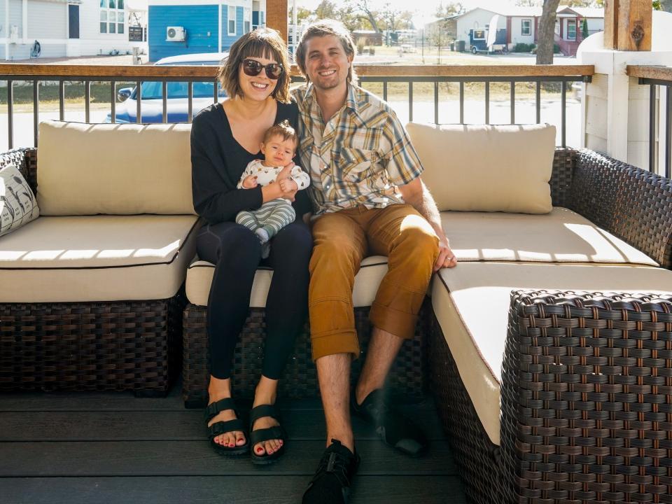 A mom, dad, and baby in the community pose for a picture on the couch in front of the community center