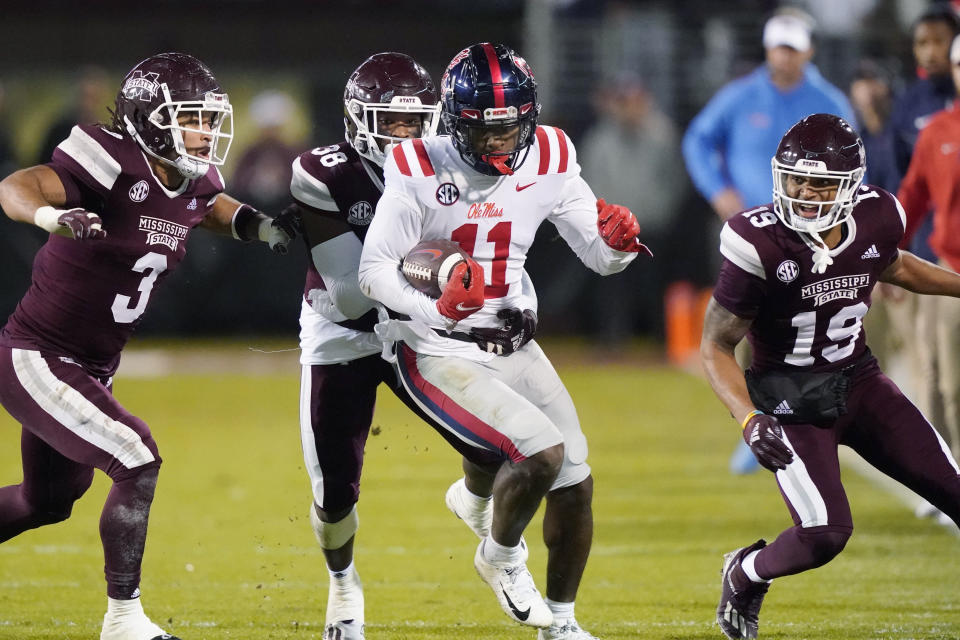 Mississippi wide receiver Dontario Drummond (11) runs past Mississippi State linebacker Aaron Brule (3) and safety Collin Duncan (19) after a pass reception during the first half of an NCAA college football game Thursday, Nov. 25, 2021, in Starkville, Miss. (AP Photo/Rogelio V. Solis)