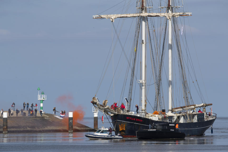 Family members watch a schooner carrying 25 Dutch teens who sailed home from the Caribbean across the Atlantic when coronavirus lockdowns prevented them flying as it arrives at the port of Harlingen, northern Netherlands, Sunday, April 26, 2020. (AP Photo/Peter Dejong)