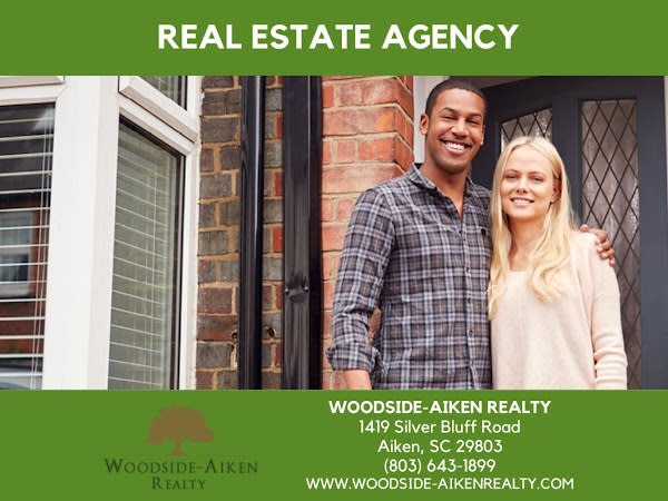 home buyers in front of house Aiken real estate agency