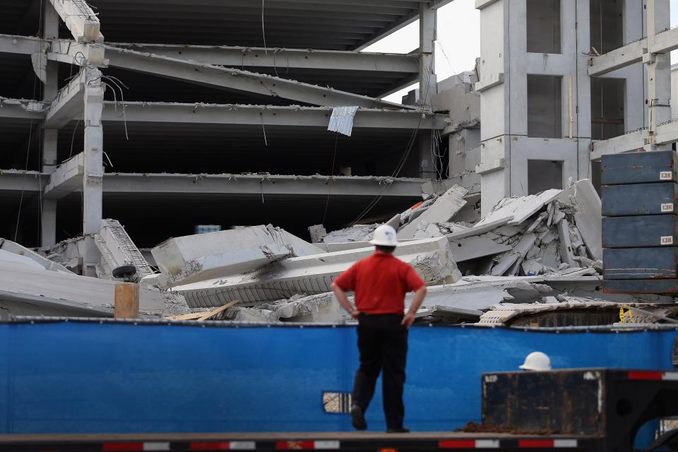 DORAL, FL - OCTOBER 10: A person looks on from a flat bed truck at the rubble of a four-story parking garage that was under construction and collapsed at the Miami Dade College’s West Campus on October 10, 2012 in Doral, Florida. Early reports indicate that one person was killed, at least seven people injured and one is still trapped. (Photo by Joe Raedle/Getty Images)