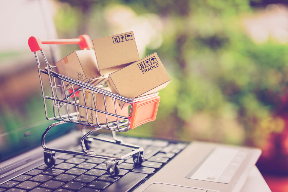 Miniature shopping cart with boxes in it on laptop keyboard