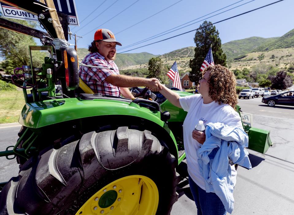 Davis County Commissioner Randy Elliott shakes hands with Celeste Maloy, congressional candidate, after Elliott drove the tractor pulling a trailer with Maloy aboard in a parade in Farmington on Saturday, July 15, 2023. | Scott G Winterton, Deseret News