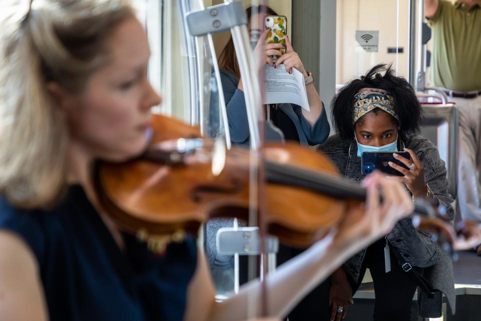 Rachel Harding Klaus, a member of the Detroit Symphony Orchestra, plays the violin inside a QLINE streetcar in Detroit on Aug. 17, 2022.