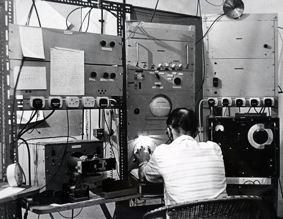 A man sitting at a high power microwave receiver receiving messages from orbiting satellites