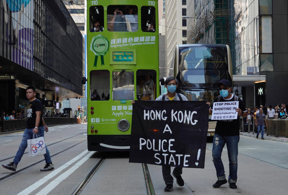 Protesters hold up a banner during a memorial flash mob to remember Chow Tsz-Lok in Hong Kong on Friday, Nov. 8, 2019. Chow, a Hong Kong university student who fell off a parking garage after police fired tear gas during clashes with anti-government protesters died Friday, in a rare fatality after five months of unrest that intensified anger in the semi-autonomous Chinese territory. (AP Photo/Vincent Yu)