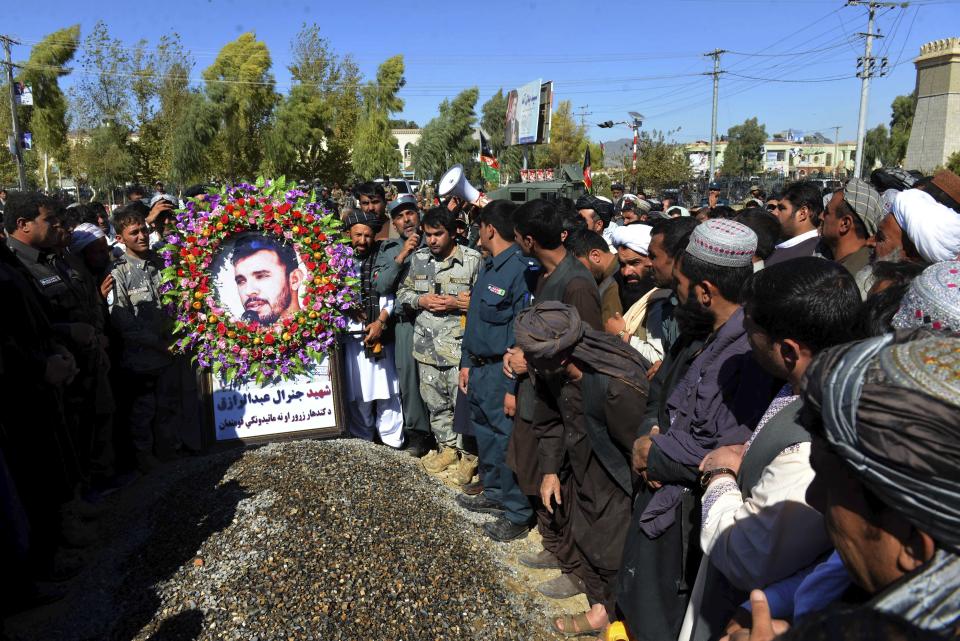 Civilians and military personnel stand beside the grave of Gen. Abdul Raziq, Kandahar police chief, who was killed by a guard, as the pay respect during his burial ceremony in Kandahar, Afghanistan, Friday, Oct. 19, 2018. Afghanistan's election commission on Friday postponed elections in Kandahar for a week, following a brazen attack on a high-profile security meeting there with a U.S. delegation that killed at least two senior provincial officials, including the province's police chief. (AP Photo)