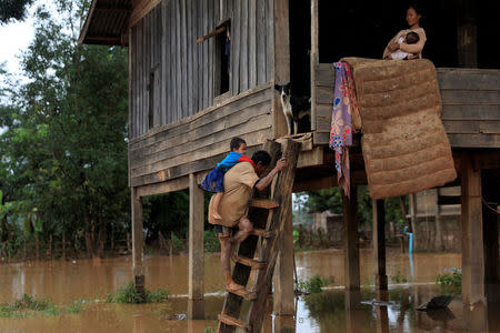 Parents carry their children as they leave their home during the flood after the Xepian-Xe Nam Noy hydropower dam collapsed in Attapeu province, Laos July 26, 2018. REUTERS/Soe Zeya Tun