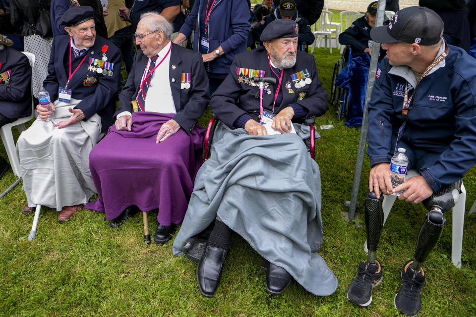 British World War II veterans speak with U.S Dan Cnossen, right, during a service at the Pegasus Bridge memorial in Benouville, Normandy, France, Wednesday, June 5, 2024. World War II veterans from across the United States as well as Britain and Canada are in Normandy this week to mark 80 years since the D-Day landings that helped lead to Hitler's defeat. (AP Photo/Virginia Mayo)